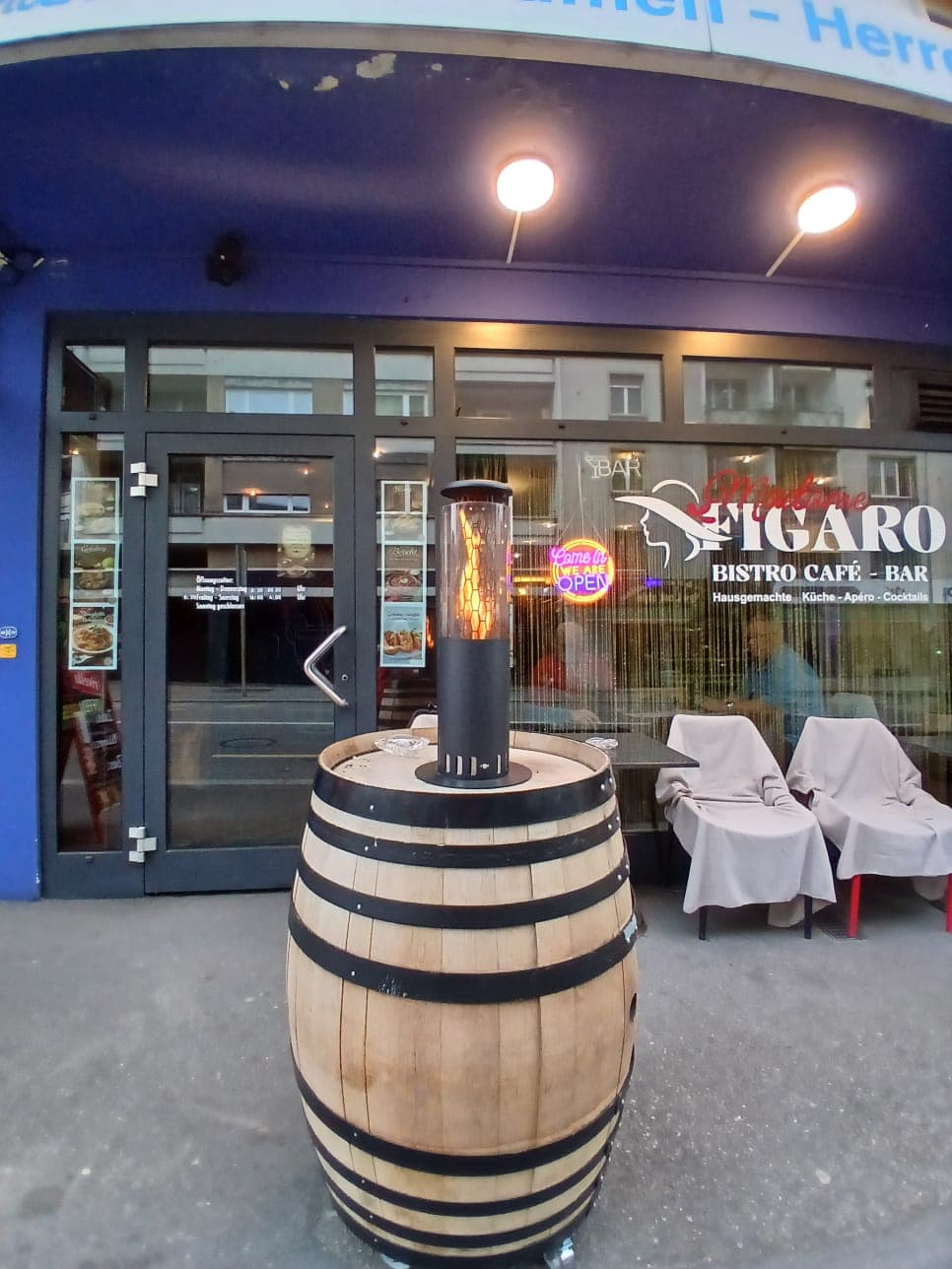 Eingang von Madame Figaro mit Fass und Terrassenplätzen
